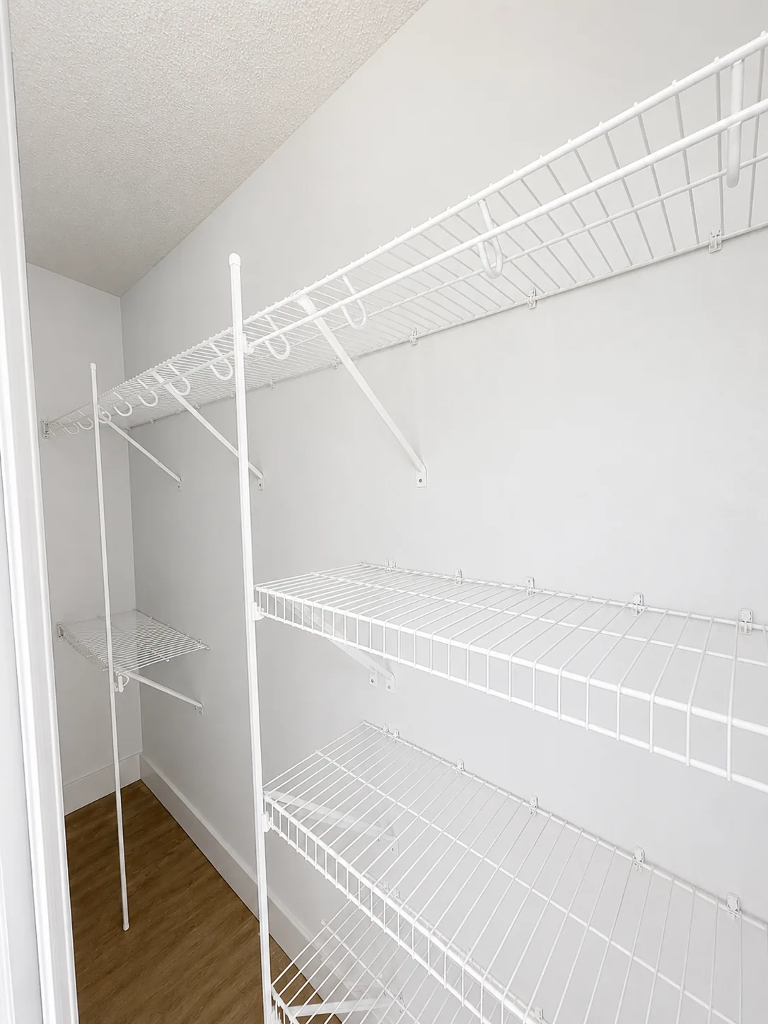 White ventilated wire shelving installed in a new-build walk-in closet